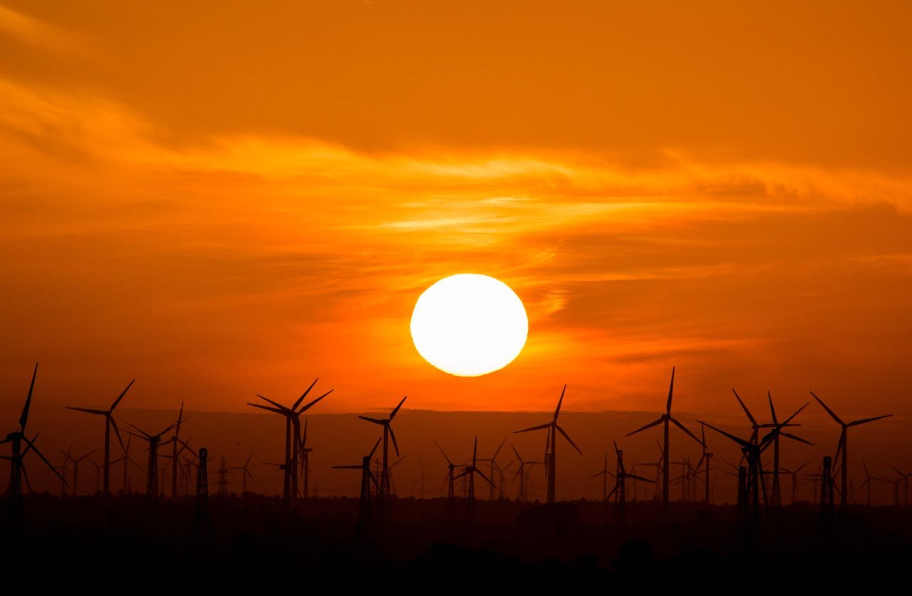 Wind turbines silhouetted against a stunning sunset, showcasing renewable energy in nature.